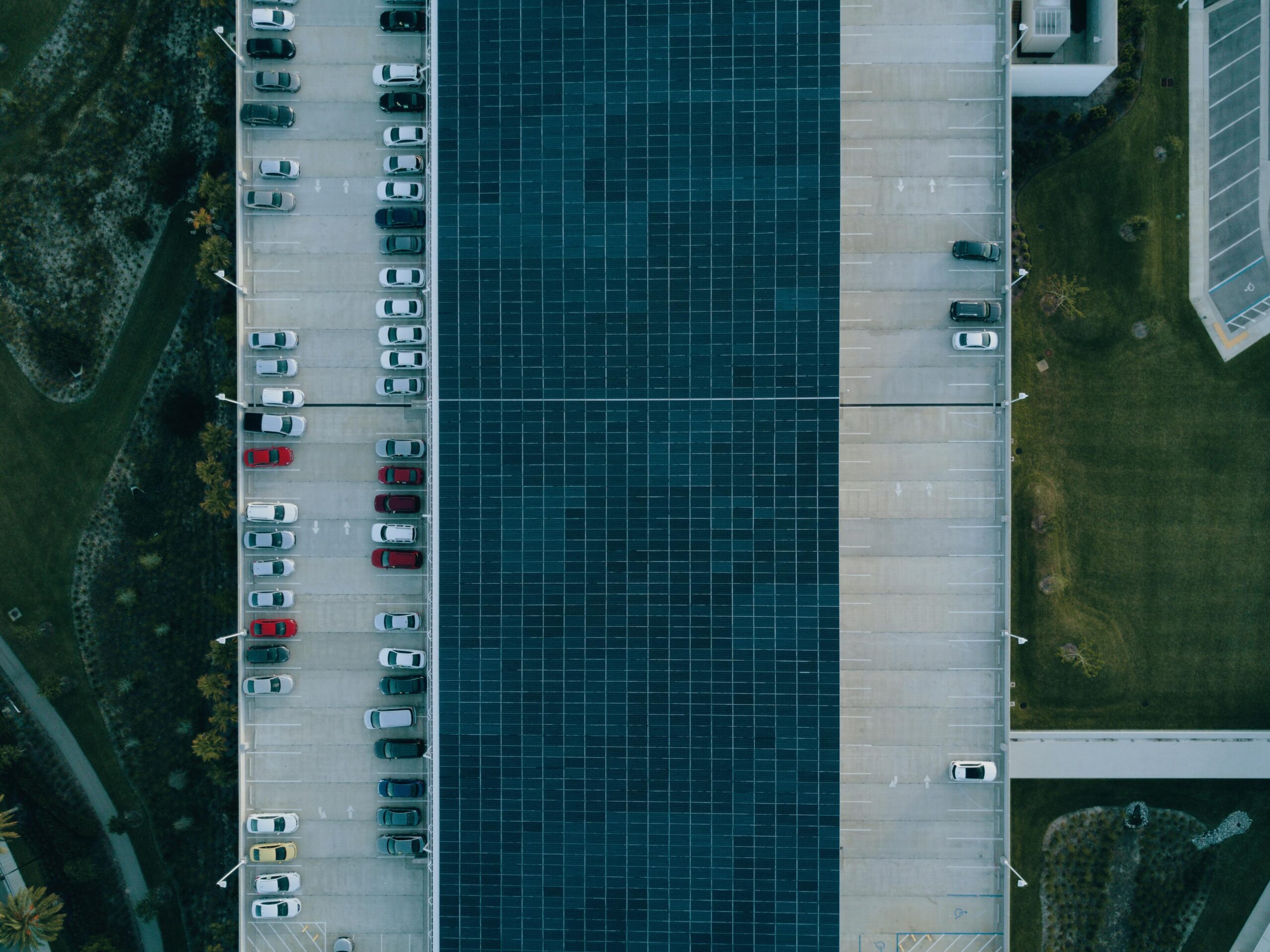 Top view of a parking lot with cars and solar panels, showcasing urban sustainability.