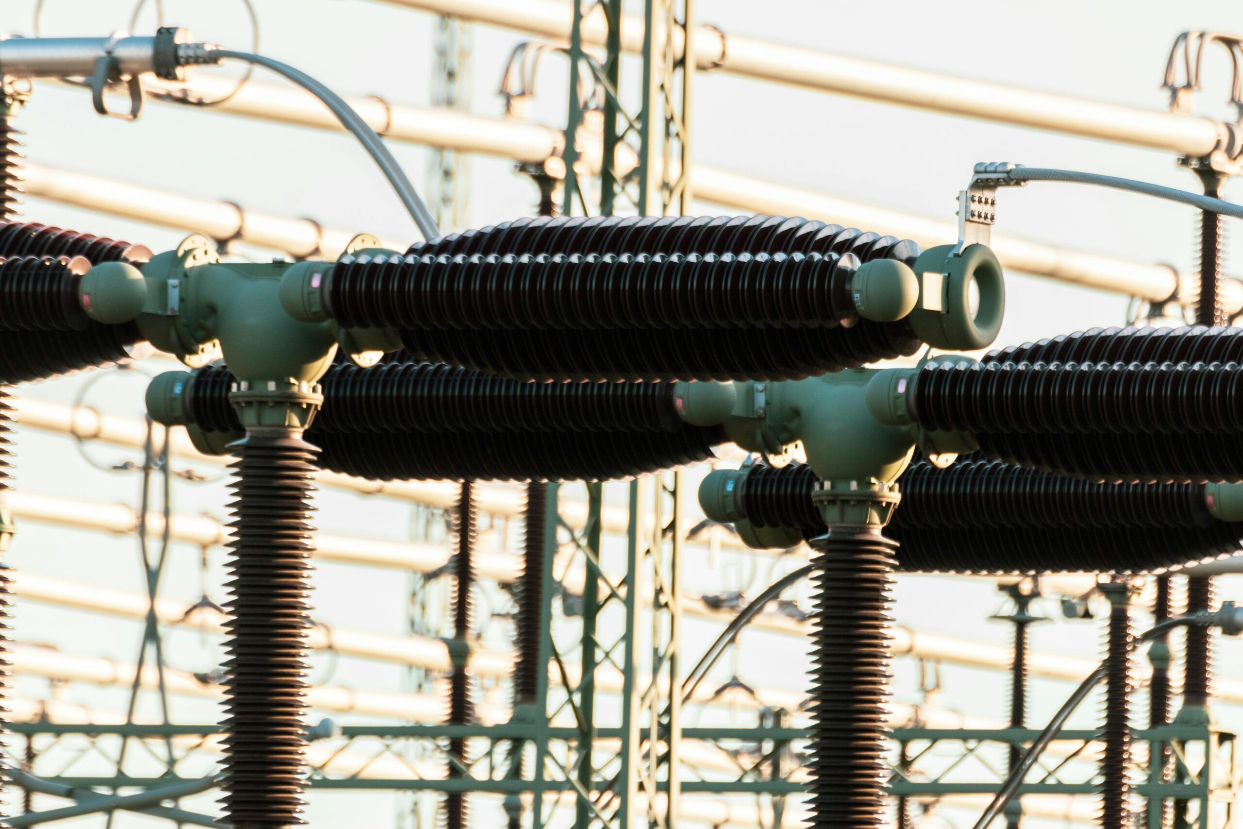 Close-up of outdoor electrical power equipment with insulators and conductors.